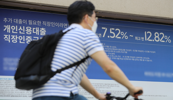 A person pedals by a banner advertising loans in Seoul on Tuesday. [NEWS1]