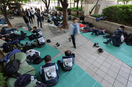 Members of the Korean Confederation of Trade Unions stage a sit-in near Cheonggye Plaza in downtown Seoul on the morning of May 17 as people walk by. [YONHAP]