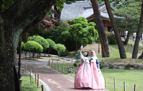 Tourists in hanbok (Korean traditional dress) pose at the Blue House on Wednesday during a hanbok event organized by the Ministry of Culture, Sports and Tourism and the Korea Craft and Design Foundation. The event, which started on Wednesday and runs through June 4, allows visitors in hanbok to walk along Nokjiwon, the largest garden in the Blue House where previous presidents hosted major events for foreign dignitaries. [YONHAP]
