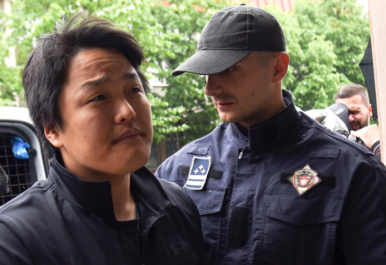 Police officers escort Korean crypto mogul Do Kwon in Podgorica, Montenegro, on May 11. Kwon, who is on trial in Montenegro for forging travel documents, is wanted in Korea, Singapore and the United States for the involvement in the collapse of his company Terraform, which is estimated to have cost investors more than $40 billion. [EPA/YONHAP]