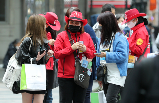 Staff of the Myeong-dong Tourist Information Center, dressed in red, provide tour information for foreigners in April. [NEWS1]