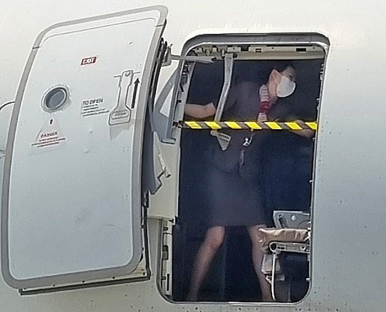 On Friday, an Asiana Airlines flight departing from Jeju landed at Daegu International Airport with the emergency exit door open. The photo captures a cabin crew member single-handedly blocking the exit. [NEWS1]