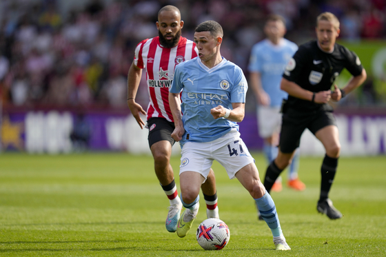 Manchester City's Phil Foden, front, duels for the ball with Brentford's Bryan Mbeumo during the Premier League match against Brentford at the Gtech Community Stadium in London on Sunday. [AP/YONHAP]