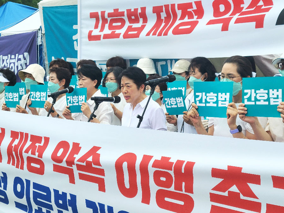 Members of the Korean Nurses' Association call on lawmakers to pass the proposed Nursing Act outside the National Assembly in Yeouido, western Seoul, on Tuesday. [YONHAP]