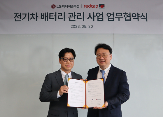  Kim Tae-young, task leader at LG Energy Solution's battery-as-a-service department, and Kim Kyoung-yeol, head of the rental car business at Redcap Tour, pose for a photo after signing an agreement Tuesday in central Seoul. [LG ENERGY SOLUTION]