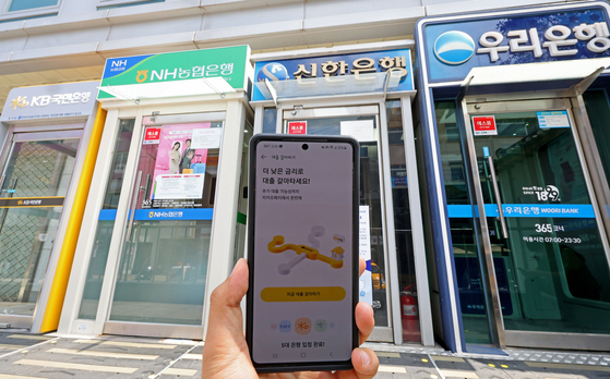  A snapshot of the newly-launched one-stop loan transfer system available via mobile app, as seen in front of ATMs installed in downtown Seoul on Wednesday. Beginning Wednesday, consumers can switch from their existing credit loans to loans offering more favorable borrowing conditions using their smartphones without having to visit a branch office of financial institutions. [YONHAP]
