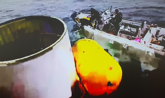 South Korean military forces retrieve a white metal cylinder that the Joint Chiefs of Staff believe was part of the North Korean space launch vehicle that crashed into the Yellow Sea on Wednesday morning. [JOINT CHIEFS OF STAFF]