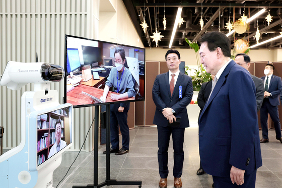 President Yoon Suk Yeol views a medical robot and connects remotely with doctors at Samsung Medical Center ahead of an export strategy meeting at the Seoul Startup Hub M+ at the Magok Industrial Complex in Gangseo District, western Seoul, Thursday. [PRESIDENTIAL OFFICE]