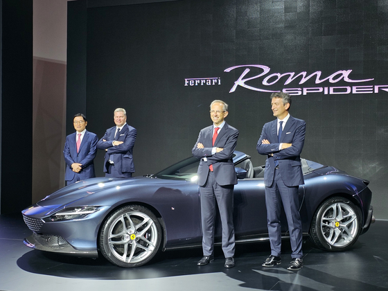 Ferrari CEO Benedetto Vigna, second from right, poses for a photo next to the Ferrari Roma Spider, a convertible sports car, displayed at the Universo Ferrari exhibition at Dongdaemun Design Plaza in Jung District, central Seoul, on Thursday.  
