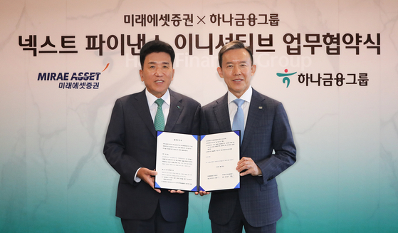 Mirae Asset Securities Chairman Choi Hyun-man, right, and Hana Financial Group Chairman Ham Young-joo pose for a photo after signing a memorandum of understanding to collaborate on the security tokens business in central Seoul on Thursday. [MIRAE ASSET SECURITIES]
