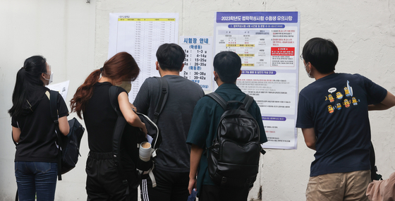 Test-takers check posters before entering the Legal Education Eligibility Test (LEET) test center in Gangnam District, southern Seoul, on July 24. The number of applicants for the LEET reached a record high of 14,620 in 2022. [YONHAP] 
