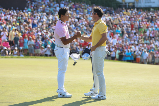 Kim Si-woo of Korea and Rory McIlroy of Northern Ireland shake hands on the 18th green during the final round of the Memorial Tournament presented by Workday at Muirfield Village Golf Club in Dublin, Ohio on Sunday.  [GETTY IMAGES]