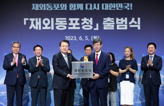President Yoon Suk Yeol, center left, presents Lee Key-cheol, center right, the inaugural head of the new Overseas Koreans Agency, with a signboard during the opening ceremony launching the new agency in Songdo, Incheon, Monday. [JOINT PRESS CORPS]