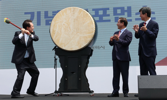 President Yoon Suk Yeol, left, beats a drum three times in a ceremony marking the launch of the new Overseas Koreans Agency held at Songdo Central Park in Incheon, Monday, with Incheon Mayor Yoo Jeong-bok, center, and Lee Key-cheol, right, the agency’s inaugural head, looking on. [JOINT PRESS CORPS]