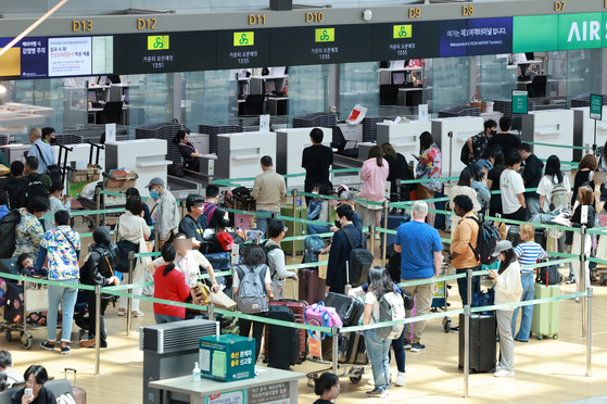 Passengers stand in line in front of a check-in counter at Incheon International Airport on Friday. [YONHAP]