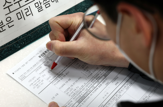 A person fills out an application for a resident registration card at a community service center in Dongjak District, southern Seoul, in January. [YONHAP]