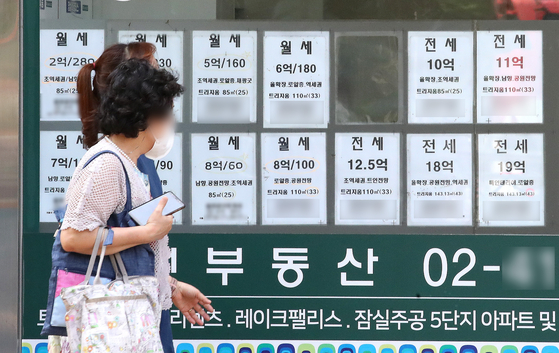 People walk pass a real estate agency in Seoul on June 21. [NEWS1]