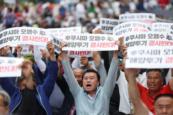Members of the Korean National Fishermen’s Association and civic groups protest near the National Assembly in Yeouido, Seoul, on Monday against the discharging of treated radioactive water from the Fukushima Daiichi Nuclear Power Plant in Japan. Japanese media over the weekend reported that Tokyo Electric Power Company (Tepco) started testing facilities to release the treated radioactive water mixed with seawater on Monday. The tests will run for two weeks. However, the official date of the discharge has yet to be decided. [YONHAP]