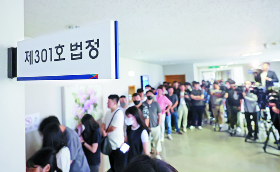 People stand in a long line awaiting the appellate court decision on a man accused of attempted murder and sexual assault of a woman in her 20s at the Busan High Court on Monday. The assailant, who knocked the woman down with a roundhouse kick near her home in Busan last year, was sentenced to 20 years in prison. [YONHAP]