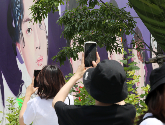 Tourists take photo of a graffiti painting of BTS near HYBE headquarters in central Seoul on Monday, created to celebrate the band's 10th anniversary of debut that falls on Tuesday. [NEWS1]