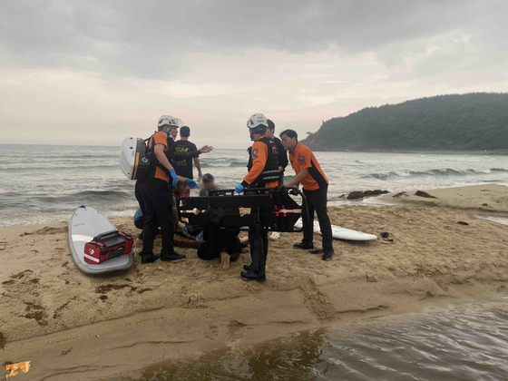 Firefighters rescue a man on Seorak Beach in Yangyang County, Gangwon on Saturday after a lightning strike. One person died and five others were injured in the accident. [YONHAP]