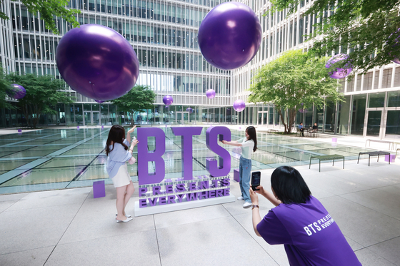 Employees of Amore Pacific visit a photo booth set up in an event zone celebrating the 10th anniversary of BTS's debut at the cosmetic companies' headquarters in Yongsan District, central Seoul, on Wednesday. The event zone, which runs in collaboration with the "2023 BTS Festa," will also exhibit a photo wall and limited-edition goods assembled by Amore Pacific. [YONHAP]