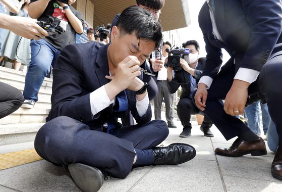 Democratic Party Rep. Jang Kyung-tae is on the ground after he collapsed while reading a written statement to oppose the government's push for separating TV license fees from electricity bills in front of the Korea Communications Commission headquarters in Gwacheon, Gyeonggi, on Wednesday. [NEWS1] 