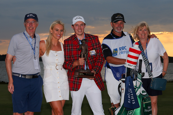 Matt Fitzpatrick celebrates with the trophy in the Heritage Plaid tartan jacket alongside father Russell Fitzpatrick second from right, girlfriend Katherine Gaal second from left, caddie Billy Foster and mother Susan Fitzpatrick after winning in a playoff during the final round of the RBC Heritage at Harbour Town Golf Links on April 16 in Hilton Head Island, South Carolina. [GETTY IMAGES]