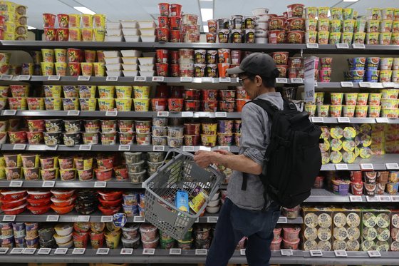 A consumer shops at the section of instant noodle products at a supermarket in Seoul on Monday. [YONHAP]