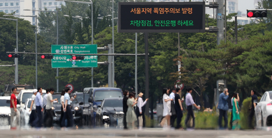Pedestrians cross a road in Yeouido, Yeongdeungpo District, western Seoul on Monday when the temperature reached above 35 degrees Celsius (95 degrees Fahrenheit). [NEWS1]