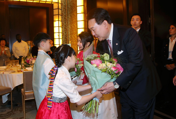 President Yoon Suk Yeol and first lady Kim Keon Hee, right, receive flowers from children during a dinner meeting with Koreans residing in France at a hotel in Paris Monday evening. [JOINT PRESS CORPS]