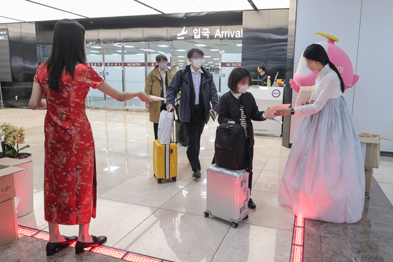 Officials from the Korea Airports Corporation dressed in traditional clothing distribute souvenirs to arriving passengers at Gimpo International Airport on March 27. [YONHAP]