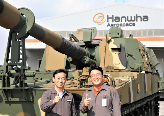 Head of Hanwha Aerospace Changwon plant and senior vice president of the company's land systems business Choi Dong-bin, left, poses for a photo in front of a K9 howitzer in Changwon, South Gyeongsang. [HANWHA AEROSPACE]