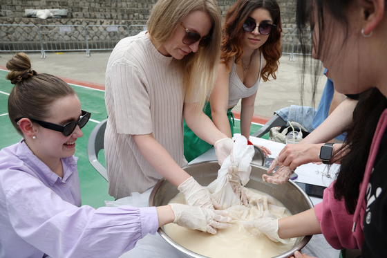 Foreign students make traditional Korean rice wine, makgeoli, during a school festival at Kyung Hee University in Seoul in May. [YONHAP]