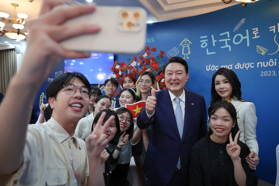 President Yoon Suk Yeol and first lady Kim Keon-hee take a selfie with Vietnamese students learning the Korean language at Vietnam National University in Hanoi Thursday during a state visit to Vietnam. [JOINT PRESS CORPS]