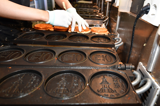 A sibwonppang store owner is making sibwonppang on the metal molds whose designs have recently come under fire by the Bank of Korea [NEWS1]