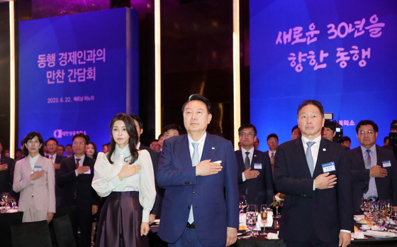 President Yoon Suk Yeol, center, first lady Kim Keon-hee, left, and SK Group Chairman Chey Tae-won, chairman of the Korea Chamber of Commerce and Industry, right, and other business leaders salute the Korean flag at a dinner banquet with the presidential business delegation at a hotel in Hanoi on Thursday. [JOINT PRESS CORPS]