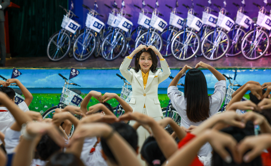 First lady Kim Keon-hee make a heart to Vietnamese at a ″Bike Run″ donation event at an SOS Children's Village school in Hanoi Thursday. [JOINT PRESS CORPS]