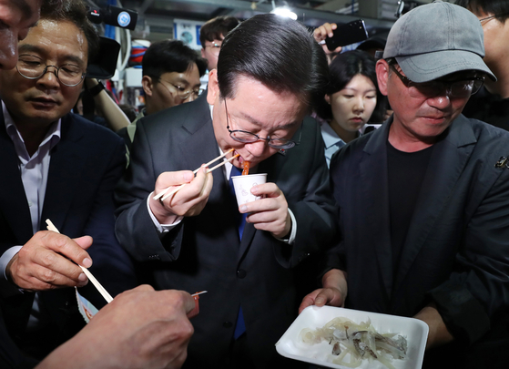 Democratic Party leader Lee Jae-myung consumes a sliced up raw squid at the Jumunjin Fish Market in Gangneung, Gangwon, Thursday as an effort to encourage fish product purchases as fish stores have been hit hard from the growing Fukushima nuclear power plant’s controversy. [YONHAP]