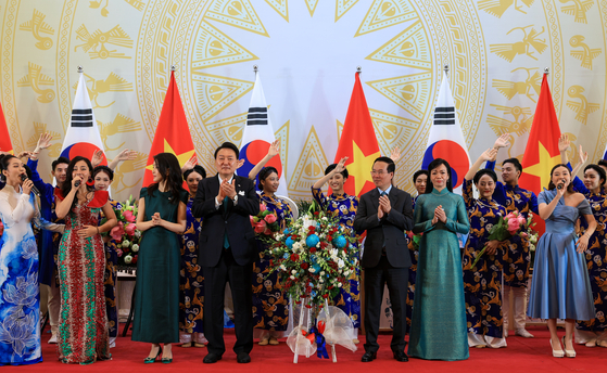 Korean President Yoon Suk Yeol, center left, accompanied by first lady Kim Keon-hee, and Vietnamese President Vo Van Thuong, center right, with first lady Phan Thi Thanh Tam, pose for a commemorative photo with performers at the state dinner at a convention center in Hanoi Friday evening. [JOINT PRESS CORPS]