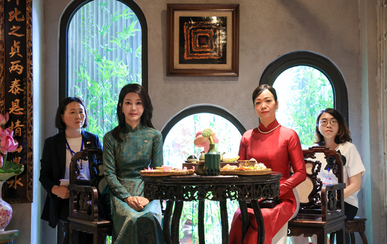 Korean first lady Kim Keon-hee, left, and Vietnamese first lady Phan Thi Thanh Tam, both dressed in ao dai, traditional Vietnamese dress, pose for a photo during a tea meeting at a restaurant in Hanoi Friday. [JOINT PRESS CORPS]