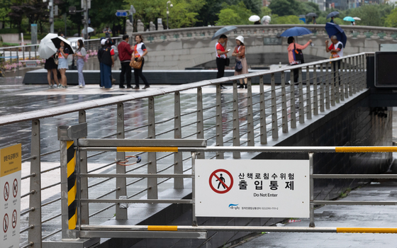 A sign at the entrance to Cheonggyecheon, a stream in central Seoul, says access is restricted due to risk of flooding amid heavy rainfall Monday morning as the monsoon season starts in Korea. [NEWS1]
