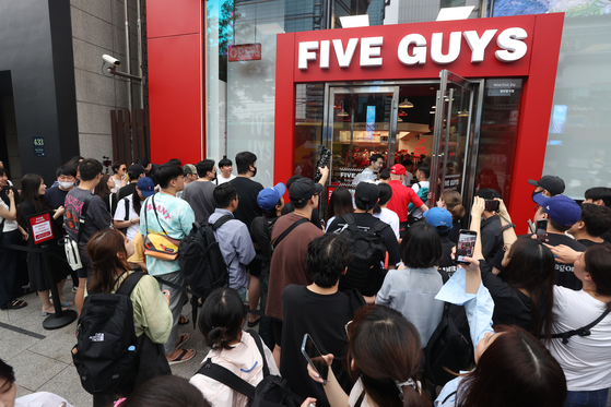 Crowds of people queue to buy burgers in front of the country's first store of U.S. made-to-order burger chain Five Guys in Gangnam District, southern Seoul, on its opening day on Monday. [YONHAP]
