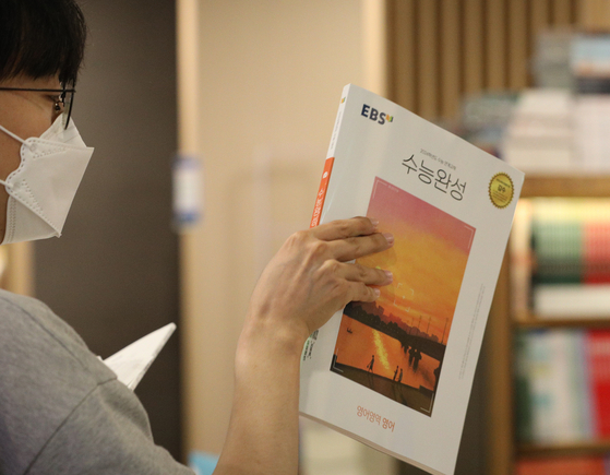 A customer picks a EBS CSAT book from Kyobo Bookstore in central Seoul on Monday. The goverment said it will not allow ″killer questions″ to be included in following CSAT. [NEWS1]