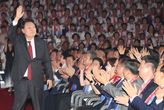 President Yoon Suk Yeol, left, waves during an event marking the 69th founding anniversary of the Korea Freedom Federation at Jangchung Arena in central Seoul on Wednesday attended by some 4,000 people. [JOINT PRESS CORPS]