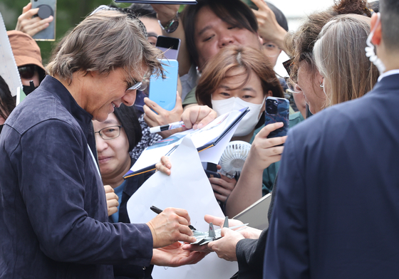 American actor Tom Cruise signs a model airplane for fans at Seoul Gimpo Business Aviation Center on Wednesday. [YONHAP]
