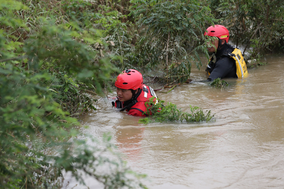 Firefighters conduct a search operation in a river in Eomda-myeon on Wednesday to locate the missing woman. [YONHAP]