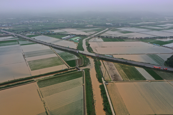 Farmlands surrounding the floodgates at the confluence of rivers in Eomda-myeon, Hampyeong County, South Jeolla, are submerged in muddy water on Wednesday. A maintenance worker in her 60s had attempted to close the floodgates on Tuesday night before going missing amid heavy rainfall. [YONHAP]