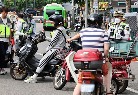 Crackdown on two-wheelers — Police crack down on traffic violations committed by users of two-wheel vehicles such as motorcycles, bicycles and personal mobility devices like electric kickboards in Gwanak, Seoul, on Wednesday. Due to the increase in accidents involving two-wheel vehicles, police are cracking down on violations for two months until Aug. 27. [YONHAP]