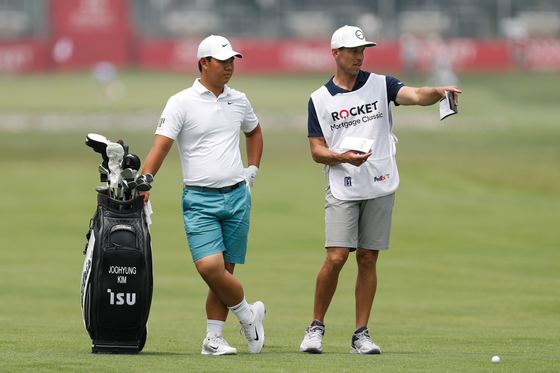 Tom Kim, also known as Kim Joo-hyung, left, stands next to his bag and caddie Joe Skovron on the 16th hole during a practice round prior to the Rocket Mortgage Classic at Detroit Golf Club on Wednesday in Detroit, Michigan. [GETTY IMAGES]